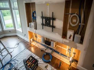 Wall-mounted TV with professional bracket, built-in shelving, ambient lighting, and organized cable management in entertainment center